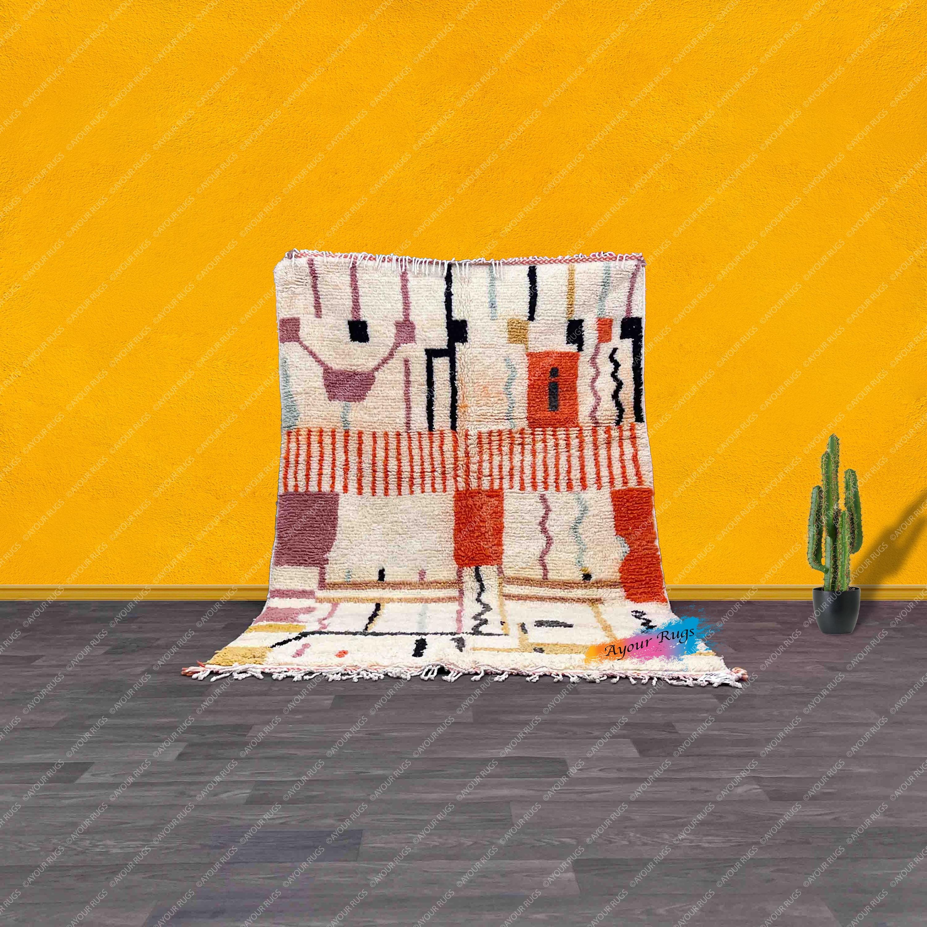 a vibrant, colorful rug with geometric patterns, placed on a wooden floor against a bright yellow wall. Next to the rug, there is a small potted cactus plant, adding a touch of greenery to the scene.