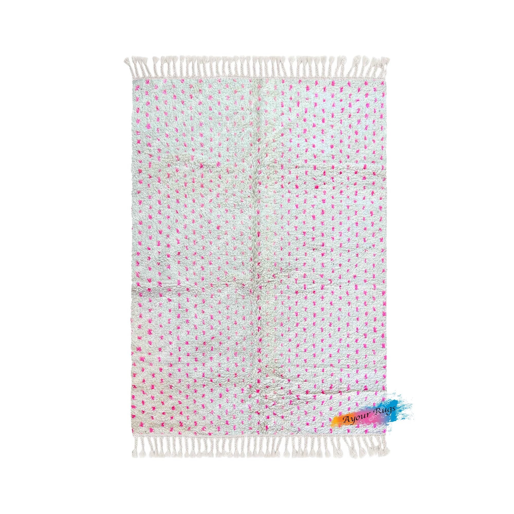 A pink and white patterned rug with a fringe design.