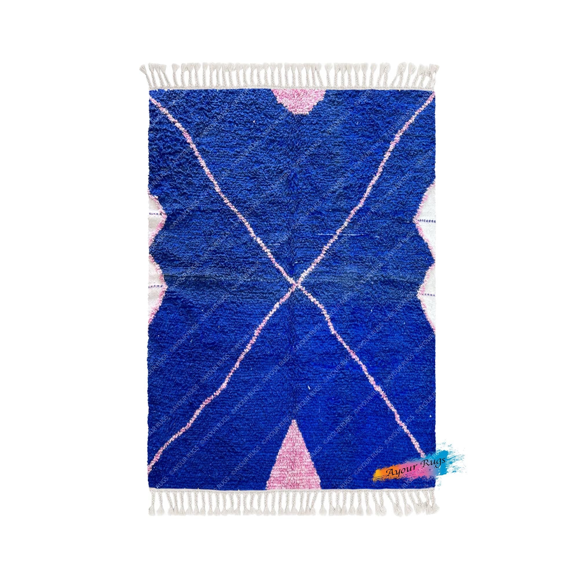 a vibrant blue and pink geometric patterned rug with a fringe at the bottom.